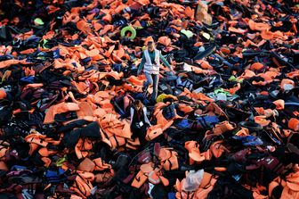 &nbsp;Volontari camminano su un mucchio di giubbotti di salvataggio lasciati da rifugiati e migranti arrivatinell'isola greca di Lesbo dopo aver attraversato il mare Egeo dalla Turchia (3 dicembre 2015)