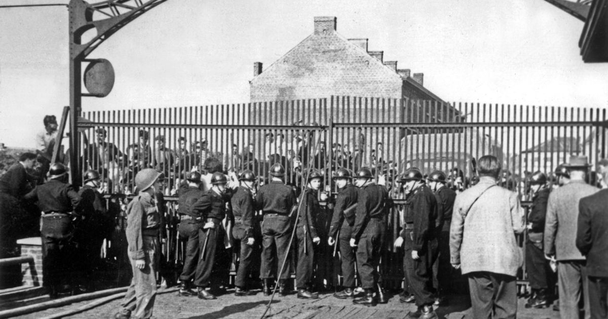 Una folla di familiari attende l'annuncio della tragedia mineraria di Marcinelle, con corpi di minatori italiani e stranieri