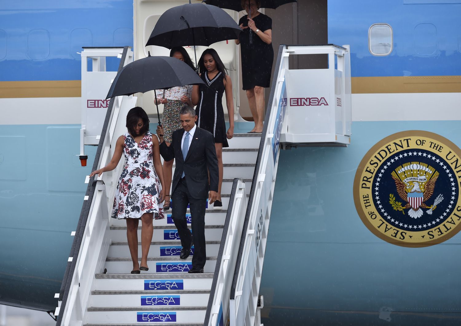 La famiglia Obama scende dall' aereo presidenziale sotto una fitta pioggia tropicale (foto Afp)