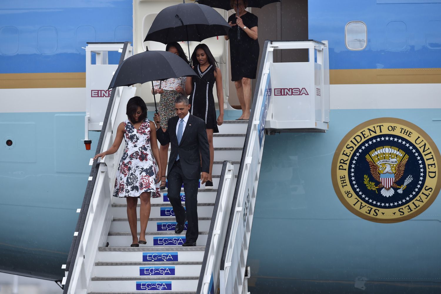 La famiglia Obama scende dall' aereo presidenziale sotto una fitta pioggia tropicale (foto Afp)