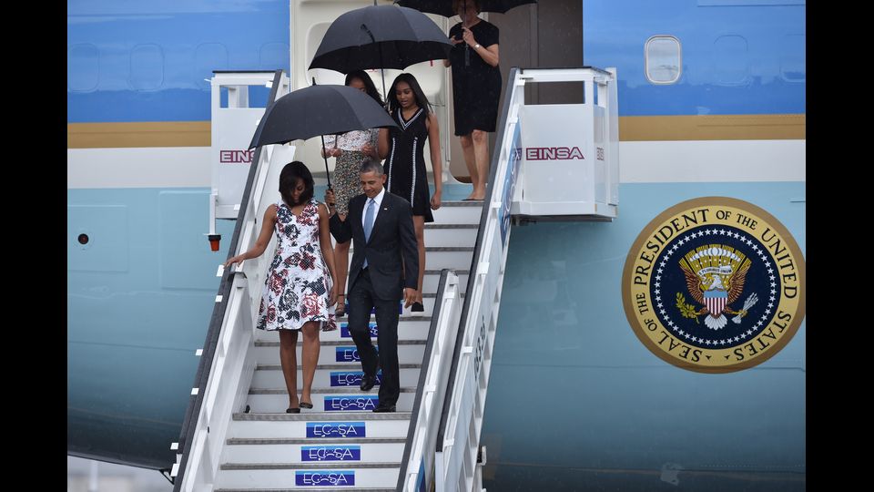 La famiglia Obama scende dall' aereo presidenziale sotto una fitta pioggia tropicale (foto Afp)
