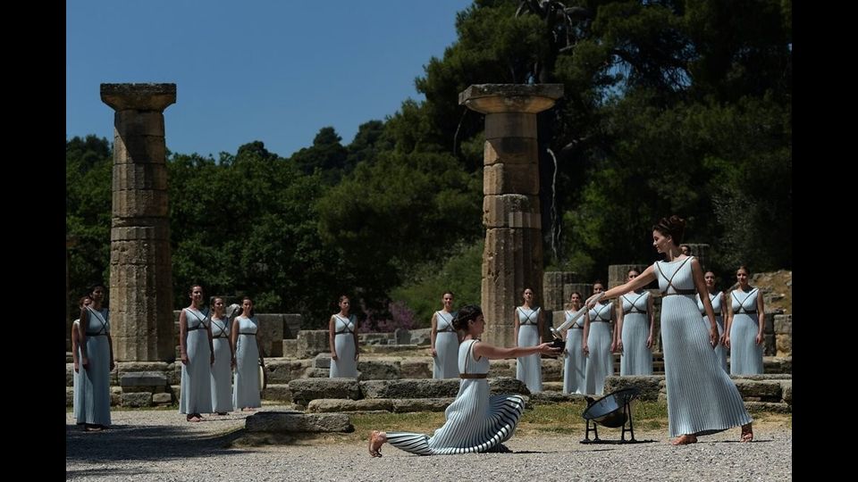 &nbsp;Katerina Lexou porge la torcia accesa con la fiamma Olimpica &nbsp;ad un'altra attrice durante la cerimonia di accensione al Tempio di Hera&nbsp;(foto Afp)