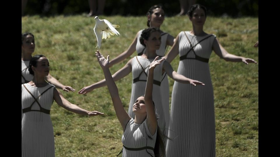 &nbsp;Un' attrice &nbsp;lancia in volo una colomba bianca durante la cerimonia di accensione della fiaccola Olimpica (foto Afp)