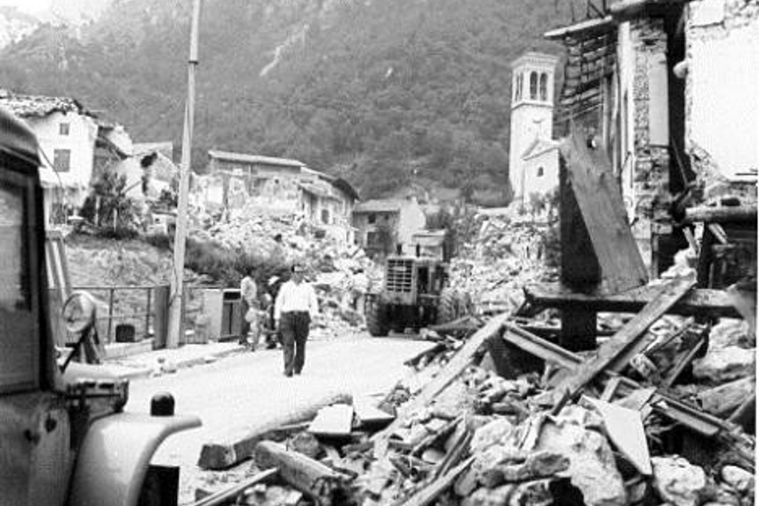 Mezzi ed uomini impegnati nello sgombero delle macerie che invadono la sede stradale impedendo il transito degli automezzi (sito Protezione Civile)&nbsp;