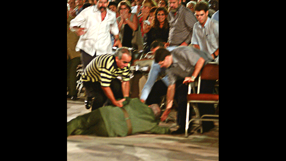 Il presidente cubano aiutato dalle sue guardie del corpo dopo una caduta al termine di un discorso (21 ottobre 2004) (Afp)&nbsp;