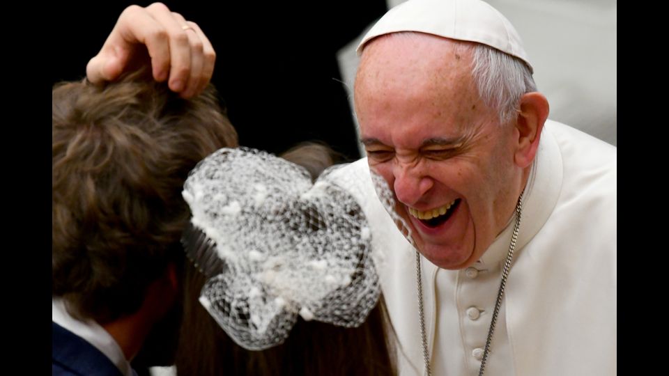 La simpatica risata di Papa Francesco mentre saluta la gente all'udienza generale nell'Aula Paolo VI  in Vaticano (Afp)