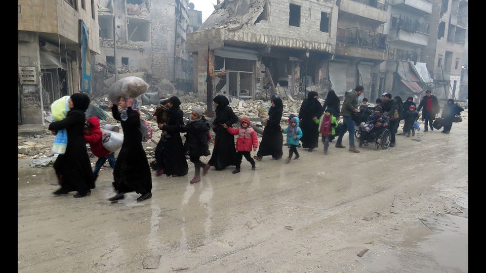 Civili in fuga mentre infuria la battaglia ad Aleppo Est (foto Afp)