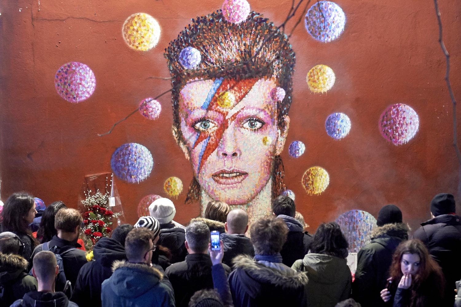 Tributo per David Bowie. Dopo l'annuncio della morte, la folla si riunisce davanti a un murale a Brixton, sud di London, l'11 gennaio 2016 (foto Afp)