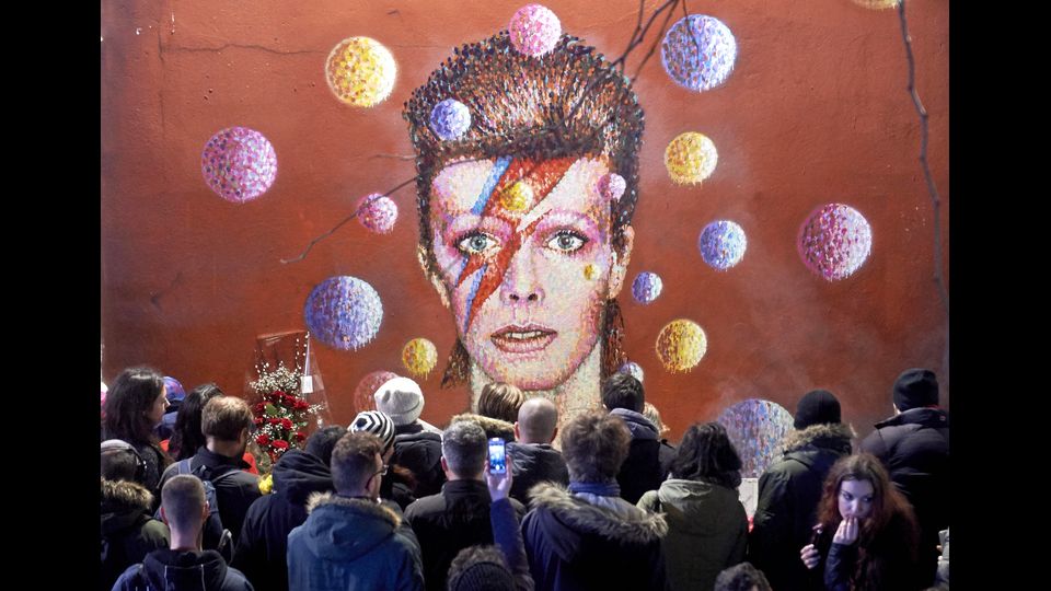 Tributo per David Bowie. Dopo l'annuncio della morte, la folla si riunisce davanti a un murale a Brixton, sud di London, l'11 gennaio 2016 (foto Afp)