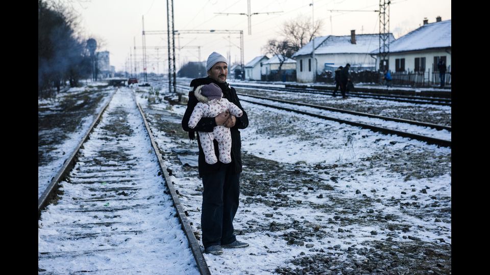 Al gelo un migrante attende il treno con il figlio, nella citt&agrave; serba di Presevo, per raggiungere l'Europa (foto Afp)