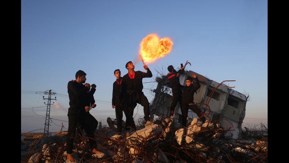 Giovani palestinesi, membri del gruppo di arti marziali di Gaza, si esibiscono a Beit Hanoun. Sullo sfondo, le rovine di una casa distrutta nel 2014 durante il conflitto tra Israele e militanti di Hamas. &nbsp;(foto Afp)