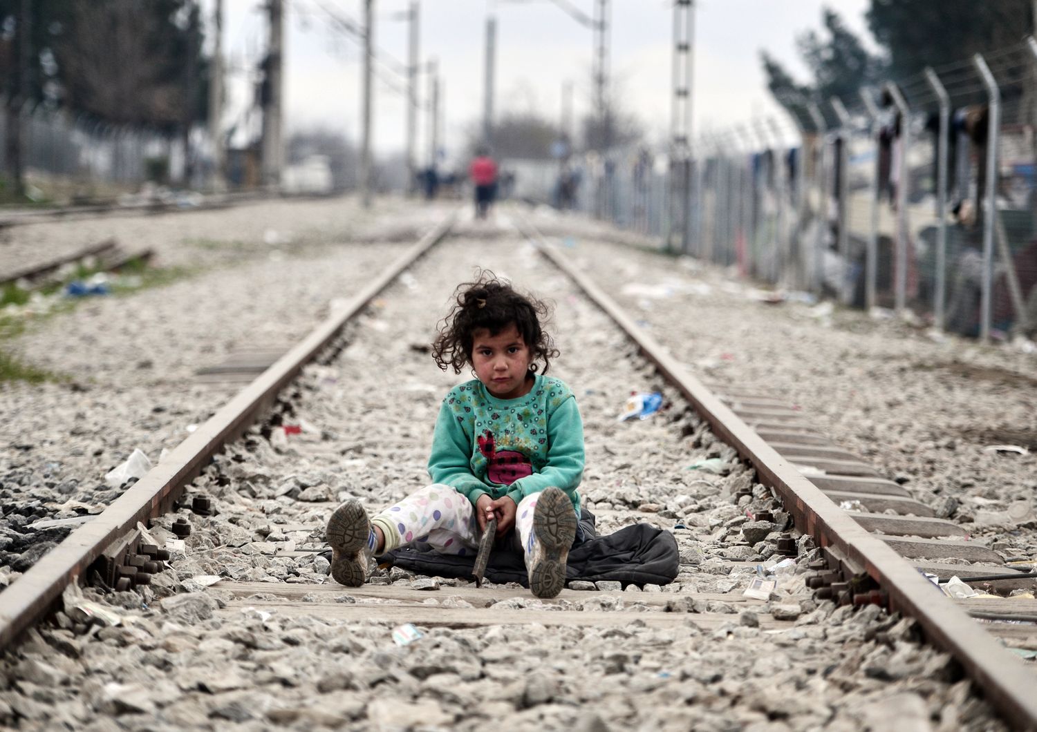 Una bambina gioca sui binari del treno lungo il confine greco-macedone, nel villaggio di Idomeni dove vivono migliaia di migranti e rifugiati. (foto Afp)