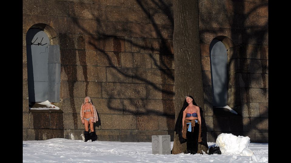 Per nulla intimorite dalla neve che ricopre la strada, due donne prendono il sole in bikini a San Pietroburgo, vicino la fortezza si Santi Pietro e Paolo. (foto Afp)