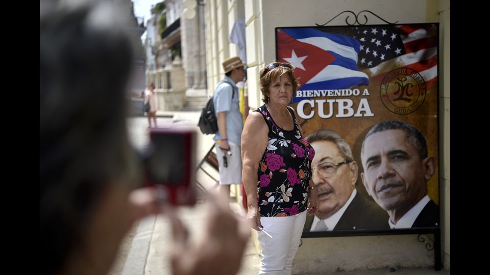 Una donna cubana per una foto davanti al manifesto di 'benvenuto' a Barack Obama, primo presidente Usa a mettere piede a Cuba dal 1928 anni. Obama e Castro si incontrano il 19 marzo a L'Avana, un incontro storico che sugella il processo di riavvicinamento tra i due Paesi. &nbsp;(foto Afp)