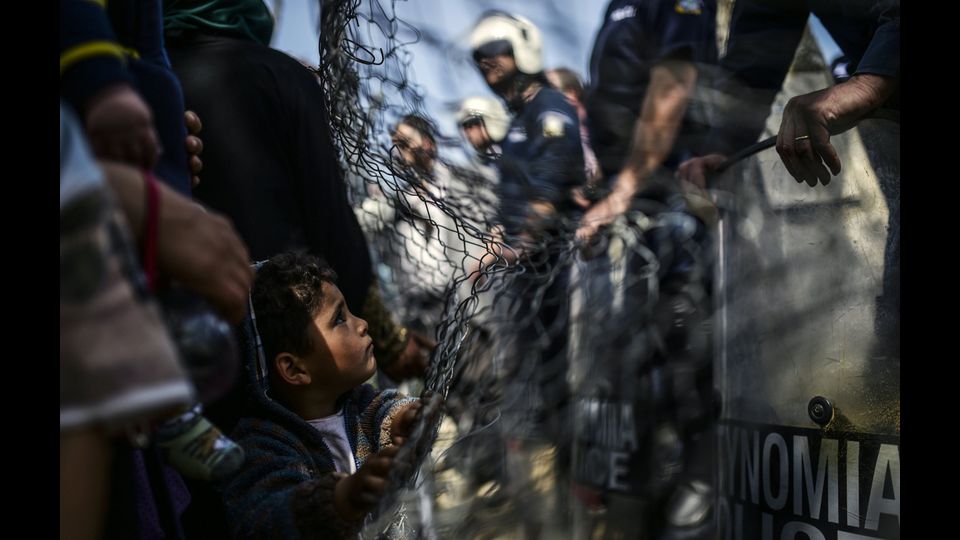 Un bambino tra gli agenti in assetto anti sommossa durante una protesta di migranti a Idomeni, in Grecia il 7 aprile 2016 (foto Afp)