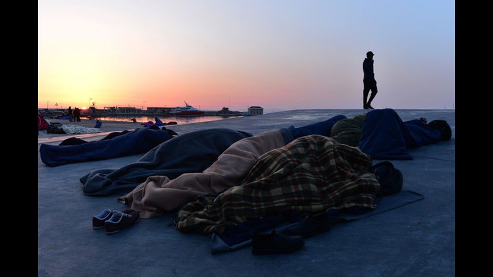 Dormire all'aperto nel porto di Chios. Un gruppo di rifugiati e migranti riescono a fuggire dal centro di accoglienza (foto Afp)