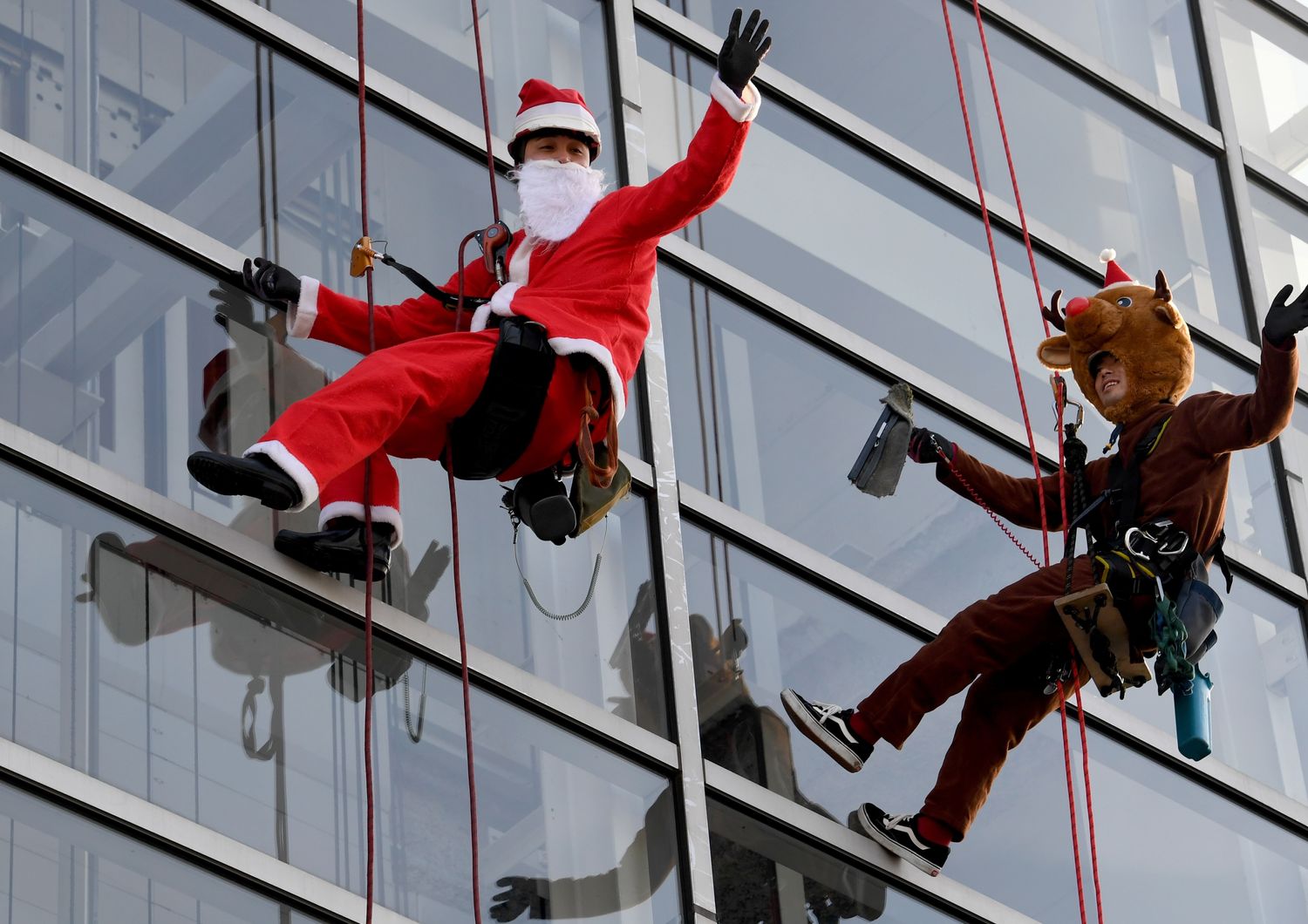 In Giappone operai mascheratii da Babbo Natale e da renna natalizia puliscono le vetrate del centro commerciale &quot;Decks Tokyo Beach&quot; (foto Afp)