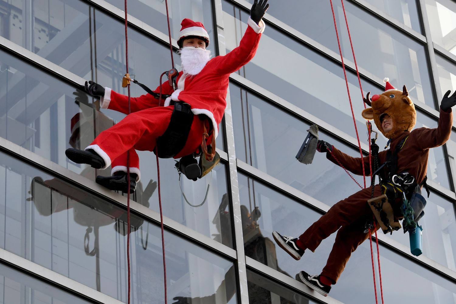 In Giappone operai mascheratii da Babbo Natale e da renna natalizia puliscono le vetrate del centro commerciale &quot;Decks Tokyo Beach&quot; (foto Afp)