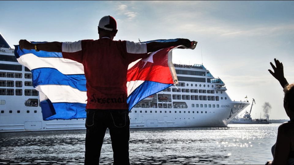 Un uomo sventola una bandiera cubana sul lungomare di Malecon all'arrivo della prima nave da crociera statunitense dopo decenni di embargo. E' il 2 maggio e la nave della Carnival &egrave; la prima ad attraccare nel porto de l'Avana dopo mezzo secolo (foto Afp)