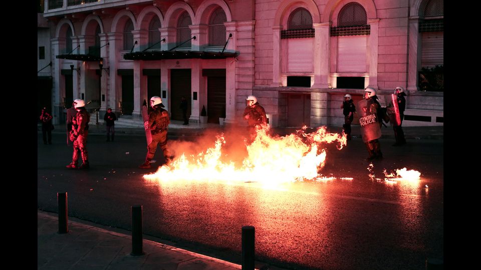 Agenti antisommossa della polizia greca tengono la posizione di fronte al lancio di molotov durante una manifestazione contro il pacchetto di riforme varato dal governo l'8 maggio (foto Afp)&nbsp;