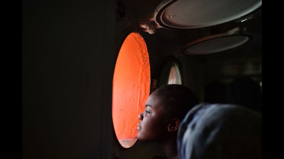 Una donna sbircia dall'obl&ograve; della nave 'Aquarius' di Medici senza frontiere che trasporta 380 migranti in Sardegna (foto Afp)&nbsp;
