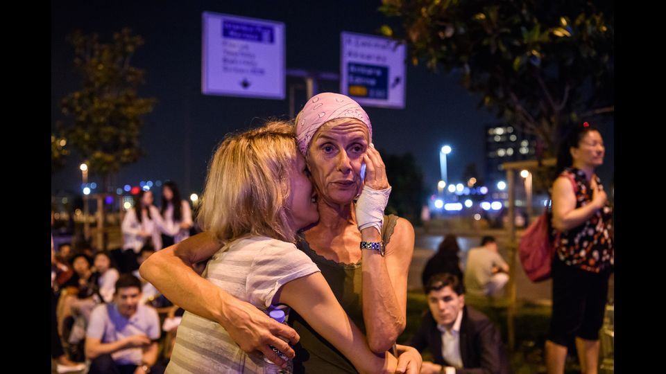Due passeggeri si abbracciano fuori dall'aeroporto Ataturk di Istanbul, preso di mira da un attacco terroristico il 28 giugno (foto Afp)