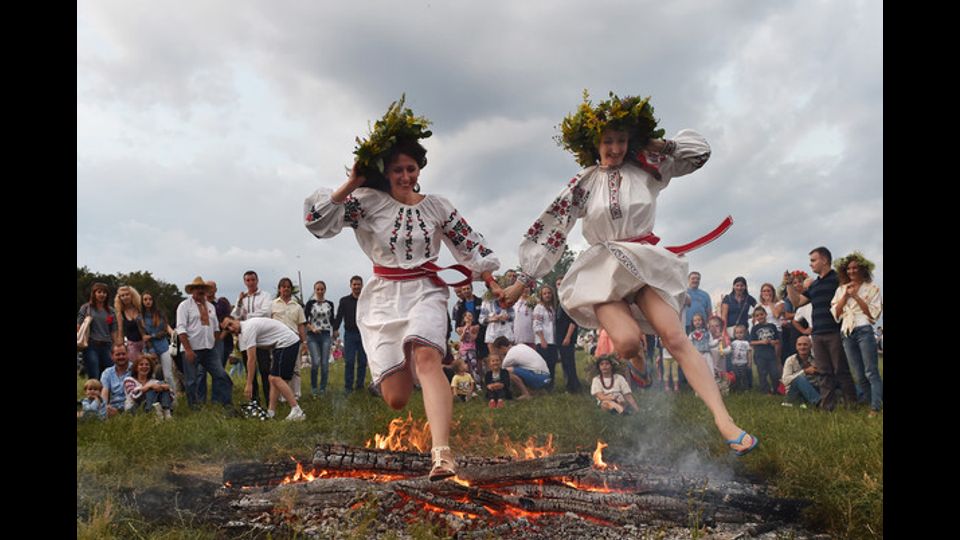 Vestite con abiti tradizionali, un gruppo di ragazze ucraine salta sul fuoco durante la notte di Ivana Kupala, un'antica festivita' pagana. La foto e' stata scattata nel villaggio di Pyrogove, vicino Kiev, il 6 luglio (foto Afp)&nbsp;