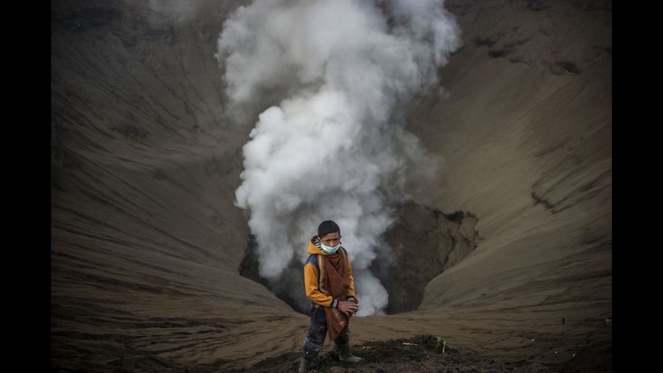 Un giovane indonesiano sul cratere del monte Bromo di Probolinggo in una tradizionale cerimonia indu' in cui si lanciano offerte nella 'bocca' del vulcano (foto Afp)&nbsp;