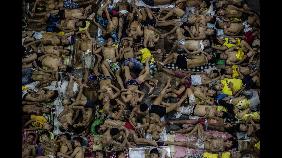In questa foto, scattata il 19 luglio, un gruppo di detenuti dorme a terra in un campo da basket nella prigione Quezon di Manila, nelle Filippine. Il carcere ospita 3.800 persone a fronte di una capienza di 800 (foto Afp)&nbsp;