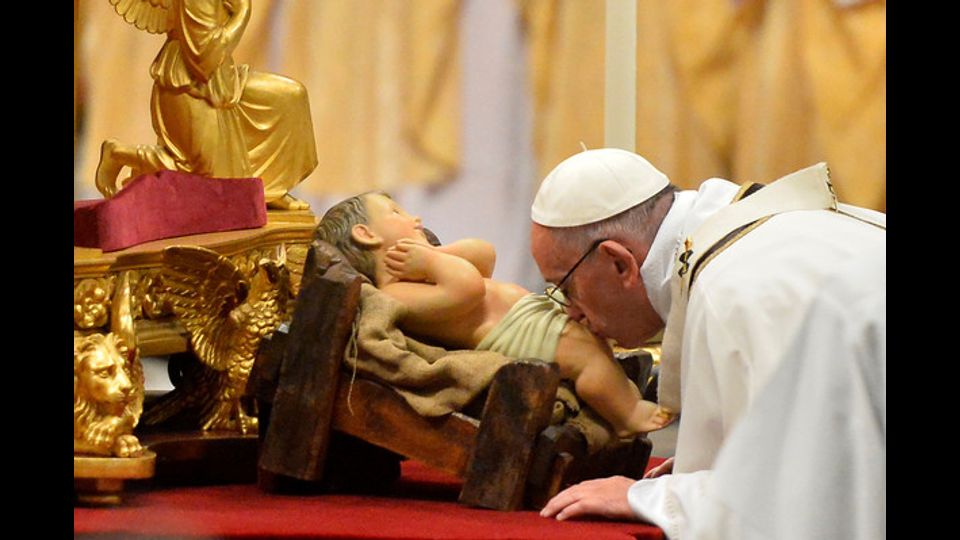 Papa Francesco bacia il Bambino Gesu' nella notte di Natale in San Pietro (foto Afp)&nbsp;