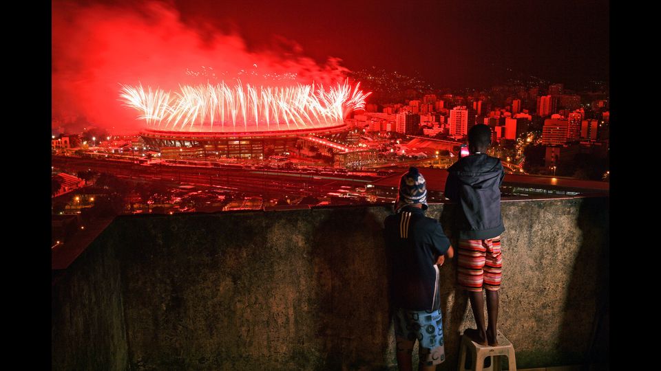Bambini della favela di Mangueira guardano i fuochi d'artificio con cui il 21 agosto a Rio si chiudono i giochi olimpici (Foto Afp)&nbsp;