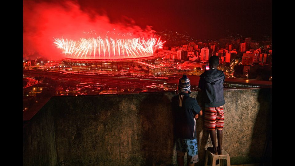 Bambini della favela di Mangueira guardano i fuochi d'artificio con cui il 21 agosto a Rio si chiudono i giochi olimpici (Foto Afp)&nbsp;