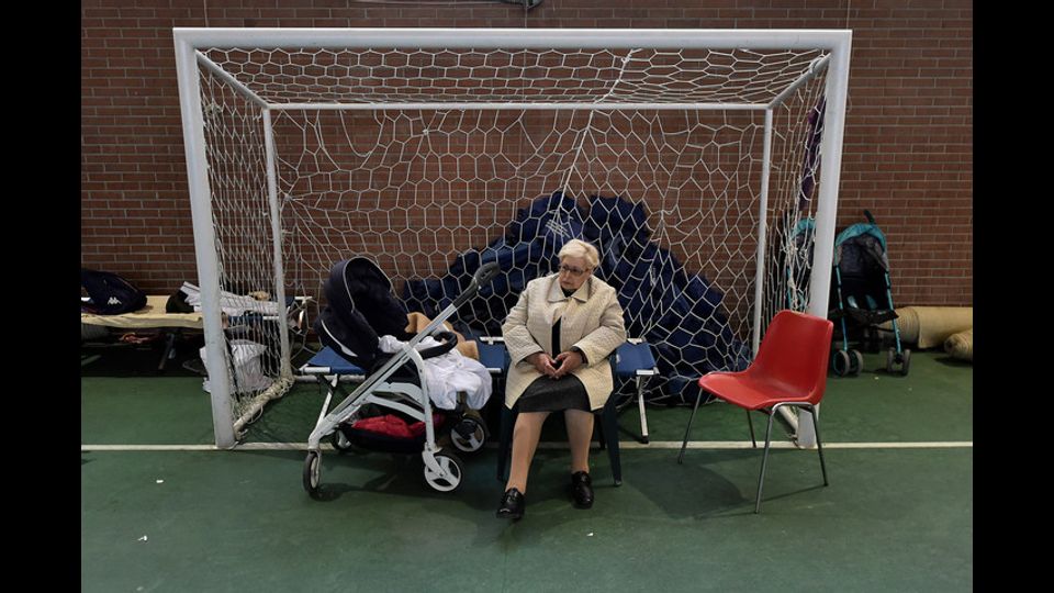 Una sfollata si siede davanti la porta di un campo da calcio di Camerino, dopo la scossa di terremoto che ha colpito il Centro Italia (foto Afp)