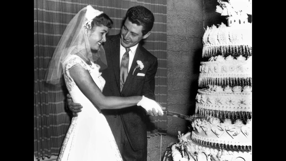 &nbsp;Debbie Reynolds e il cantante Eddie Fisher tagliano la torta nuziale nel giorno del loro matrimonio, il 26 settembre 1955 (foto Afp)