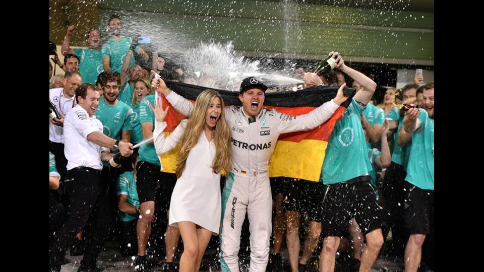 La squadra della Mercedes AMG Petronas F1 celebra la vittoria del primo titolo mondiale di Formula Uno da parte di Nico Rosberg. Nella foto, fiumi di champagne sul pilota e la moglie Vivian Sibold (foto Afp)