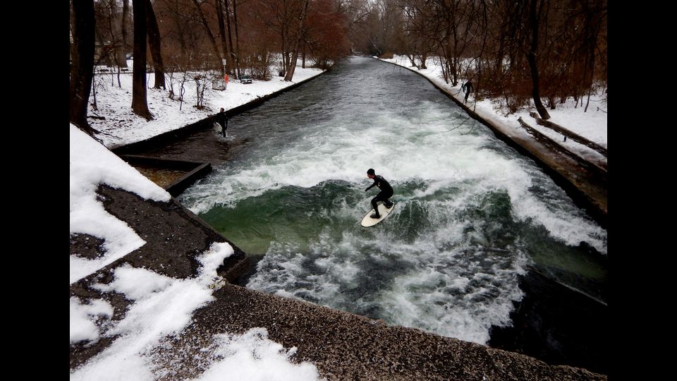 Gli amanti del surf non si lasciano spaventare dalla neve. E a Monaco di Baviera, cavalcano le onde gelide del canale dell'Eisbach, il piccolo fiume artificiale che attraversa l'Englischer Garten - il 'Giardino Inglese'- pi&ugrave; precisamente Prinzregentenstra&szlig;e, a pochi passi dal centro della citt&agrave;. Nonostante il mare disti oltre 500 chilometri, negli ultimi 45 anni nonostante il divieto di balneazione, l'Eisbach &egrave; diventato una tappa imperdibile per chi si cimenta nel&nbsp;'river surfing'&nbsp;. A detta dei pi&ugrave; esperti, fare surf sull&rsquo;onda anomala dell&rsquo;Eisbach &egrave; difficile per via della corrente e del poco spazio a disposizione tra le due sponde del fiume. (foto Afp)