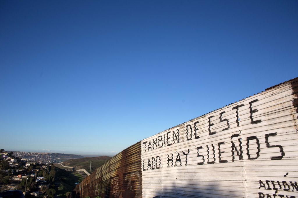 Una scritta sul muro lungo la linea di confine tra il Messico e gli Stati Uniti a Tijuana (foto Afp)