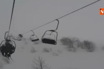 Prato nevoso sciatori in seggiovia in balia del vento