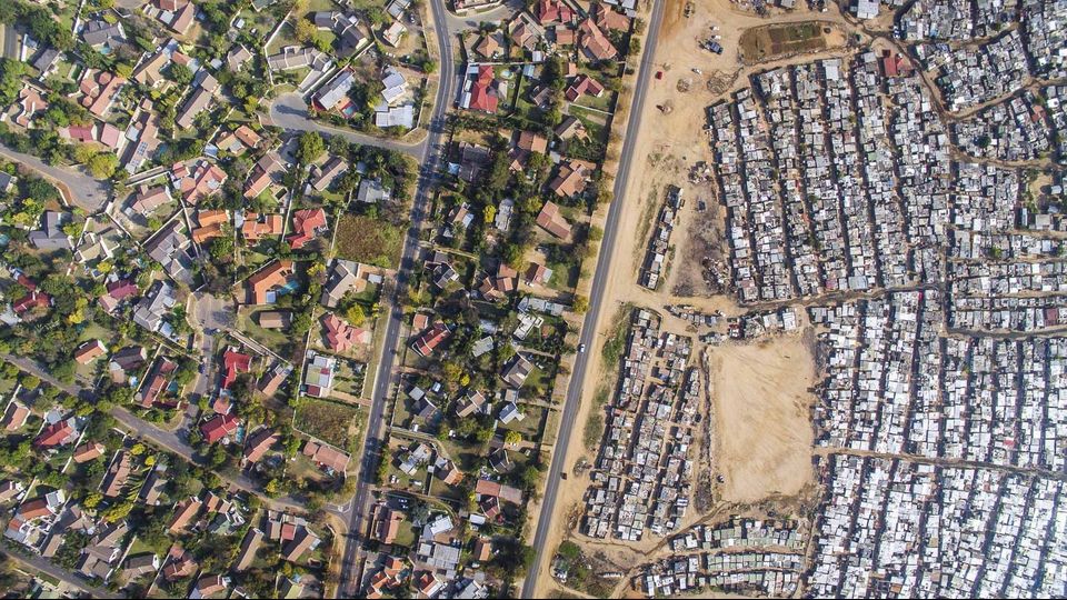 Il quartiere di Kya Sands a Johannesburg &egrave; una zona disseminata di insediamenti spontanei, perlopi&ugrave; baraccopoli, costruite da persone in cerca di fortuna nel cuore dell'economia sudafricana. Il governo &egrave; talvolta intervenuto per migliorarne le condizioni fornendo i servizi basici, ma questi sono spesso insufficienti. Le manifestazioni di protesta sono state molte. Nel 2008 si sono anche verificati episodi di violenza.   Appena dall&rsquo;altra parte della strada si trova il quartiere residenziale di Bloubosrand, dove alcune case valgono pi&ugrave; di un milione di Rand, la moneta sudafricana (circa 75.000 dollari).