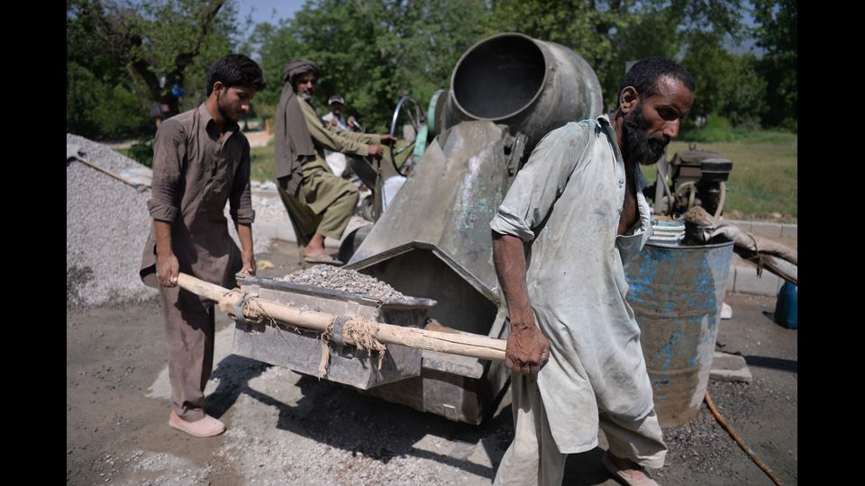 Pakistan - I lavoratori pakistani riempiono la ghiaia in un miscelatore per preparare il cemento a Islamabad durante la Giornata Internazionale del Lavoro (Afp)&nbsp;
