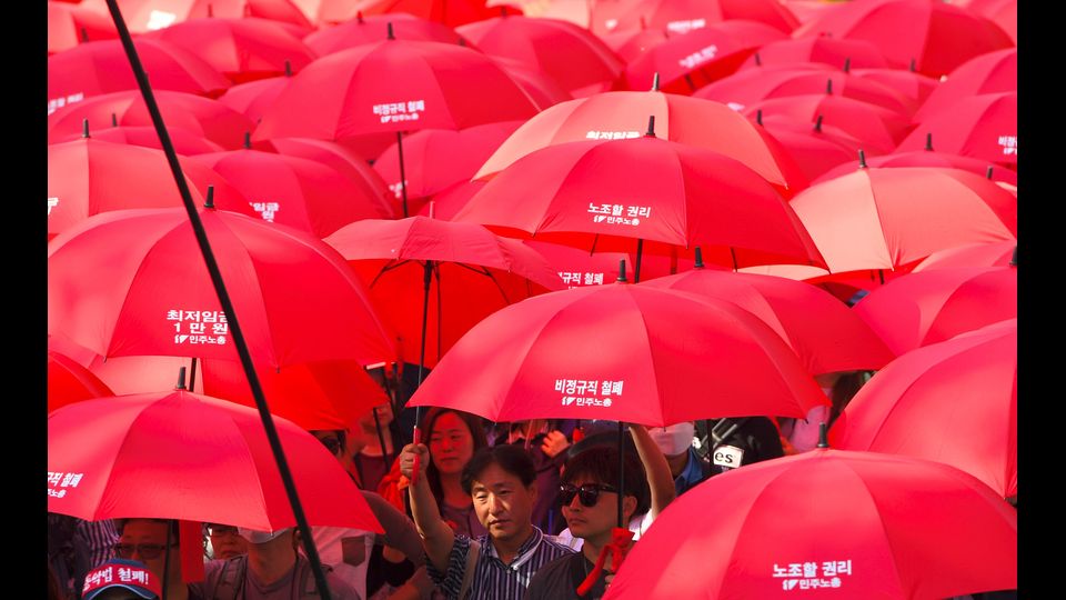 Sud Corea - Lavoratori portano ombrelli rossi durante una manifestazione per il 1 maggio a Seul. Migliaia di sudcoreani hanno partecipato alle proteste per richiedere pi&ugrave; diritti del lavoro e chiedono un salario minimo pi&ugrave; elevato. (Afp)&nbsp;