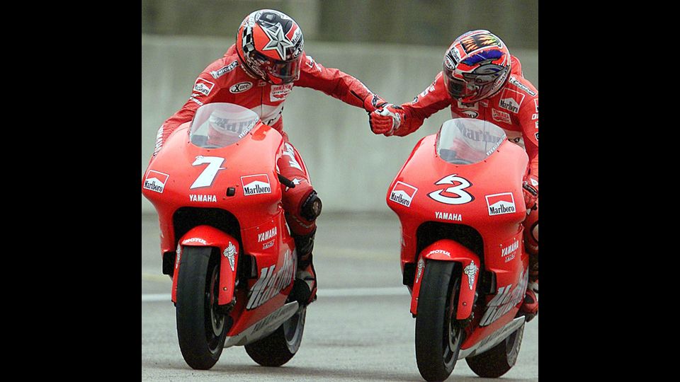 Max Biaggi e il pilota spagnolo Carlos Checa (7) a bordo delle loro Yamaha si stringono la mano dopo il GP di Rio, 3 novembre 2001