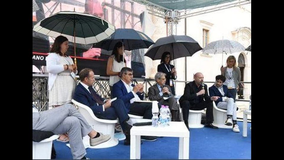 Dietro i sette uomini seduti sette ragazze con ombrelli in mano a far ombra. Una trovata per sopportare il caldo poco elegante, che ha scatenato la rabbia e le accuse di sessismo della rete