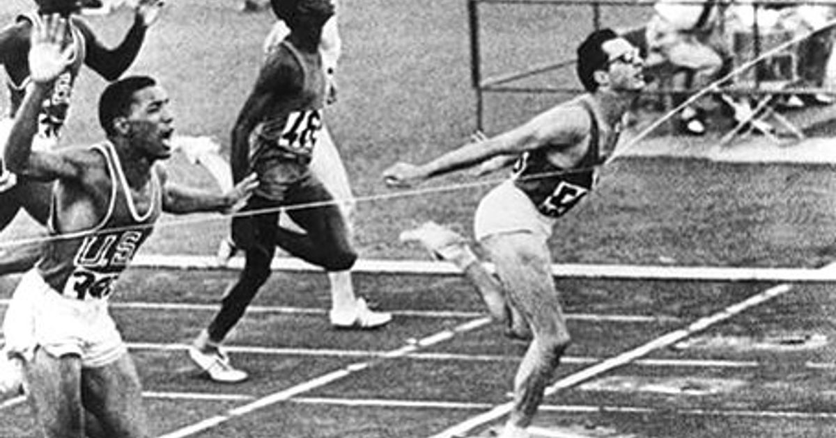 Un atleta italiano corre in pista, con bandiere a mezz'asta e un momento di silenzio per ricordare un campione, immagine di approfondimento