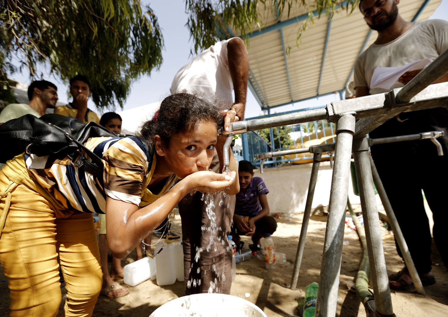 Una bambina beve acqua da uno dei punti di distribuzione installati da Oxfam