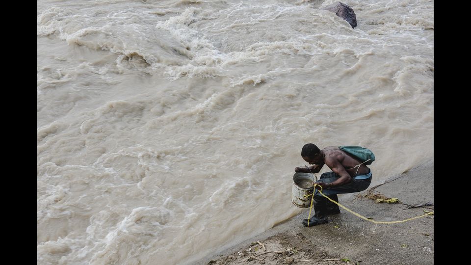 Un uomo cerca di raccogliere l'acqua da un fiume di Roseau, dopo il passaggio dell'uragano Maria (Afp)&nbsp;