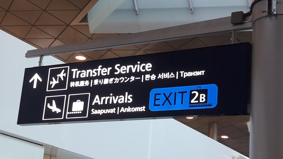 Un particolare di un tabellone che segnala in varie lingue l'accesso all'area transfer