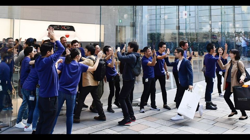 Le file sono state gestite grazie a dei braccialetti con scritto il numero del proprio turno. A festeggiare i primi tenaci clienti, i dipendenti dell'Apple Store. A Tokyo commessi e acquirenti si danno il cinque.