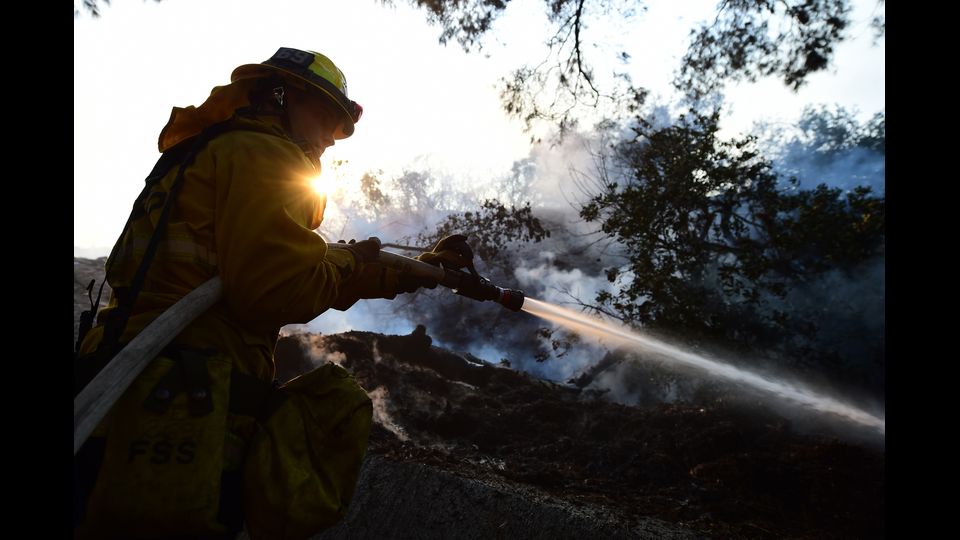 Un vigile del fuoco controlla le fiamme che bruciano in una casa allo Skirball Fire nella sezione di Bel-Air di Los Angeles in California