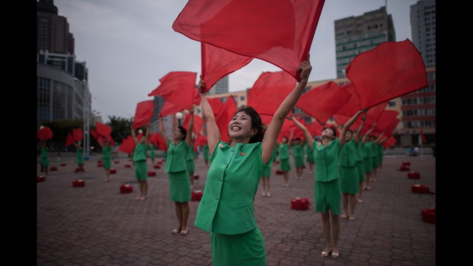 Un gruppo di ragazze si esibisce sventolando bandiere fuori dalla stazione centrale di Pyongyang